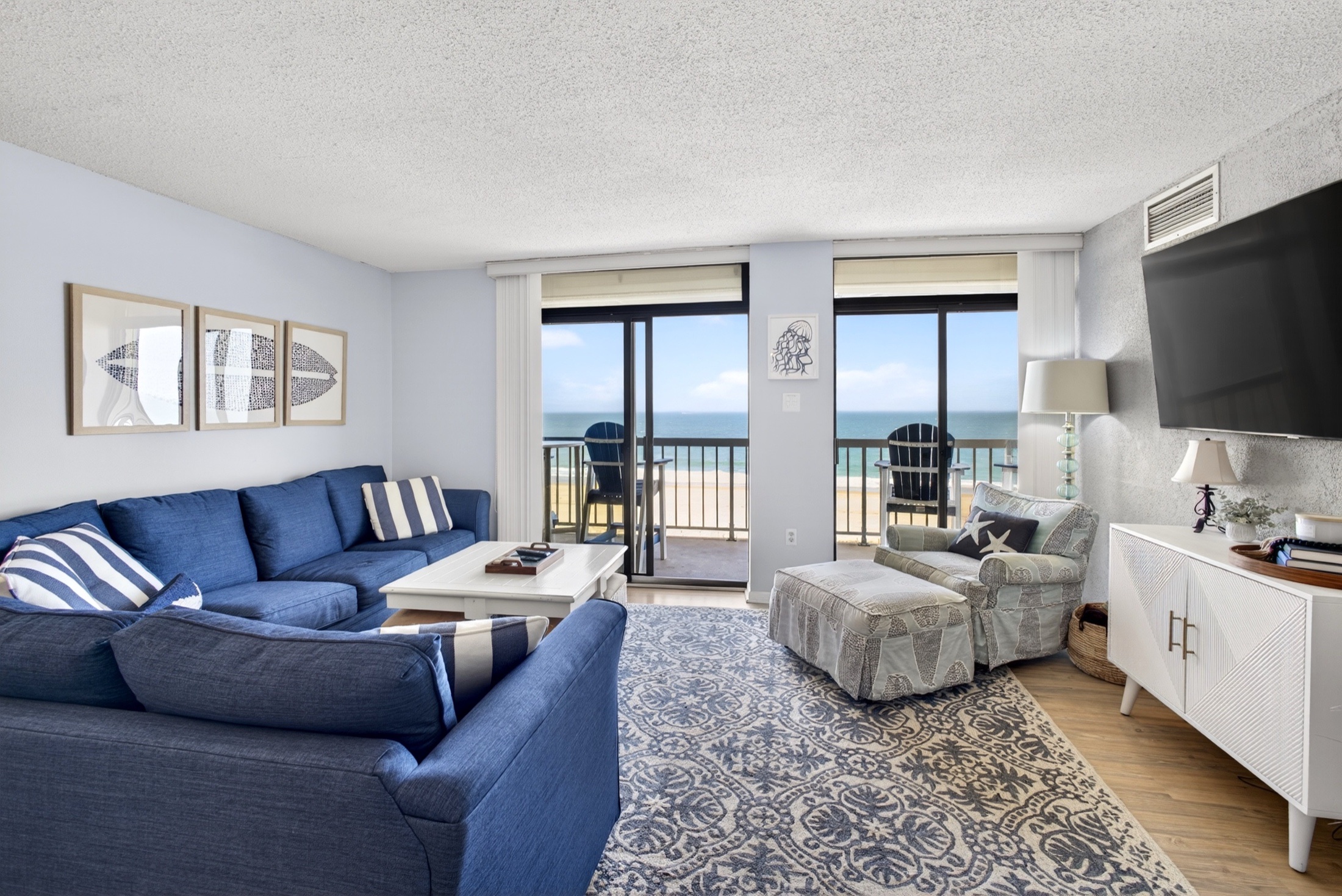 Syracuse Airbnb photography — living room with blue sectional and ocean-view balcony